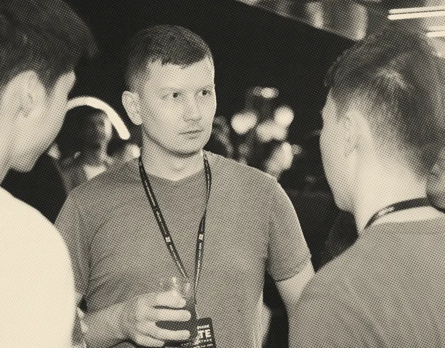 Ilia listening in a group conversation at an evening industry event